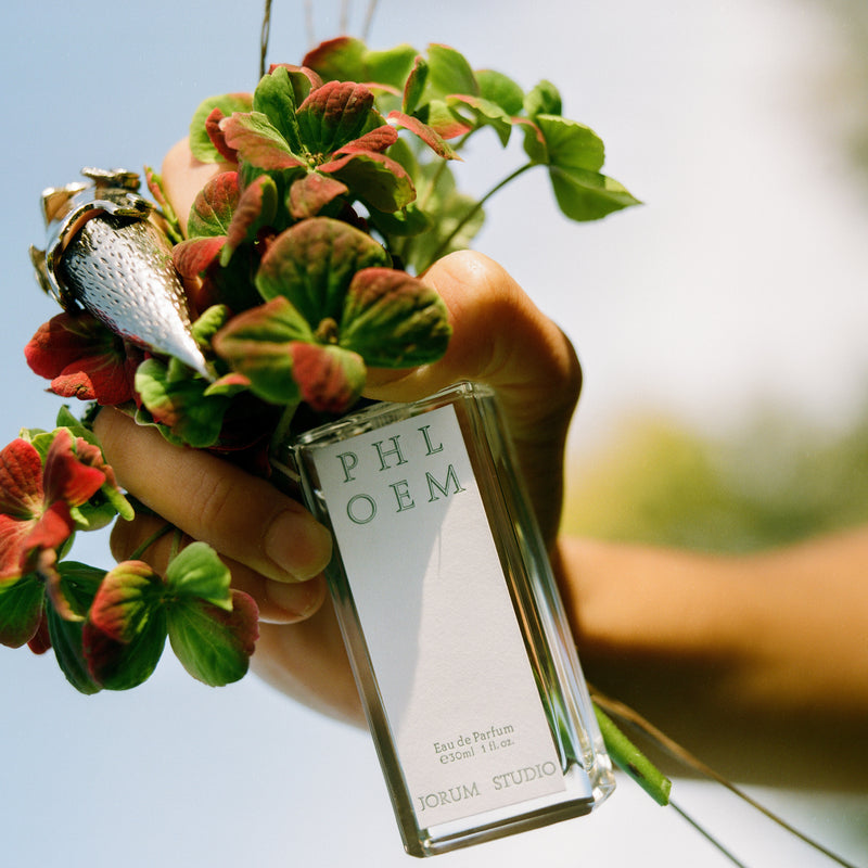 Craig McIntosh photograph of hand with pointed metal claw ring holding Jorum Studio Phloem perfume bottle and flowers
