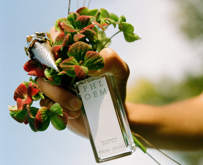 Craig McIntosh photograph of hand with pointed metal claw ring holding Jorum Studio Phloem perfume bottle and flowers