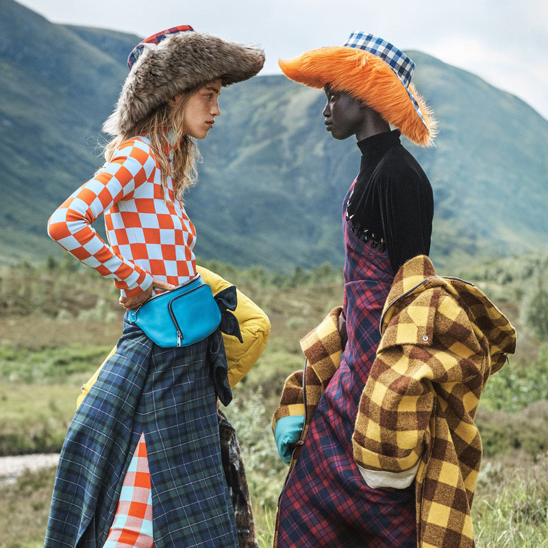 Two models in a highland setting wearing tartans and cowboy hats