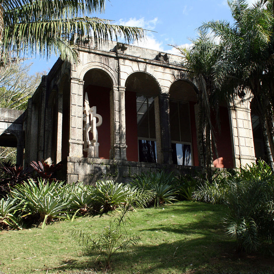 A large stone building with arches surrounded by lush greenery and palm trees