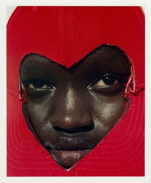 woman's face peeking through red fabric in the shape of a heart