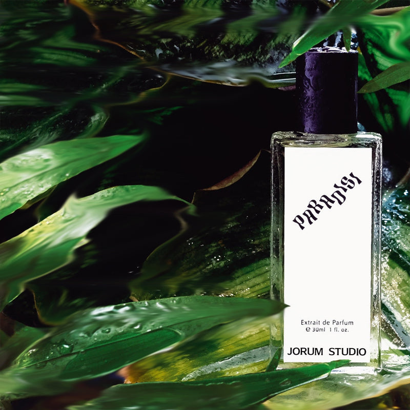 Bottle of Paradisi Perfume amongst dewy green leaves