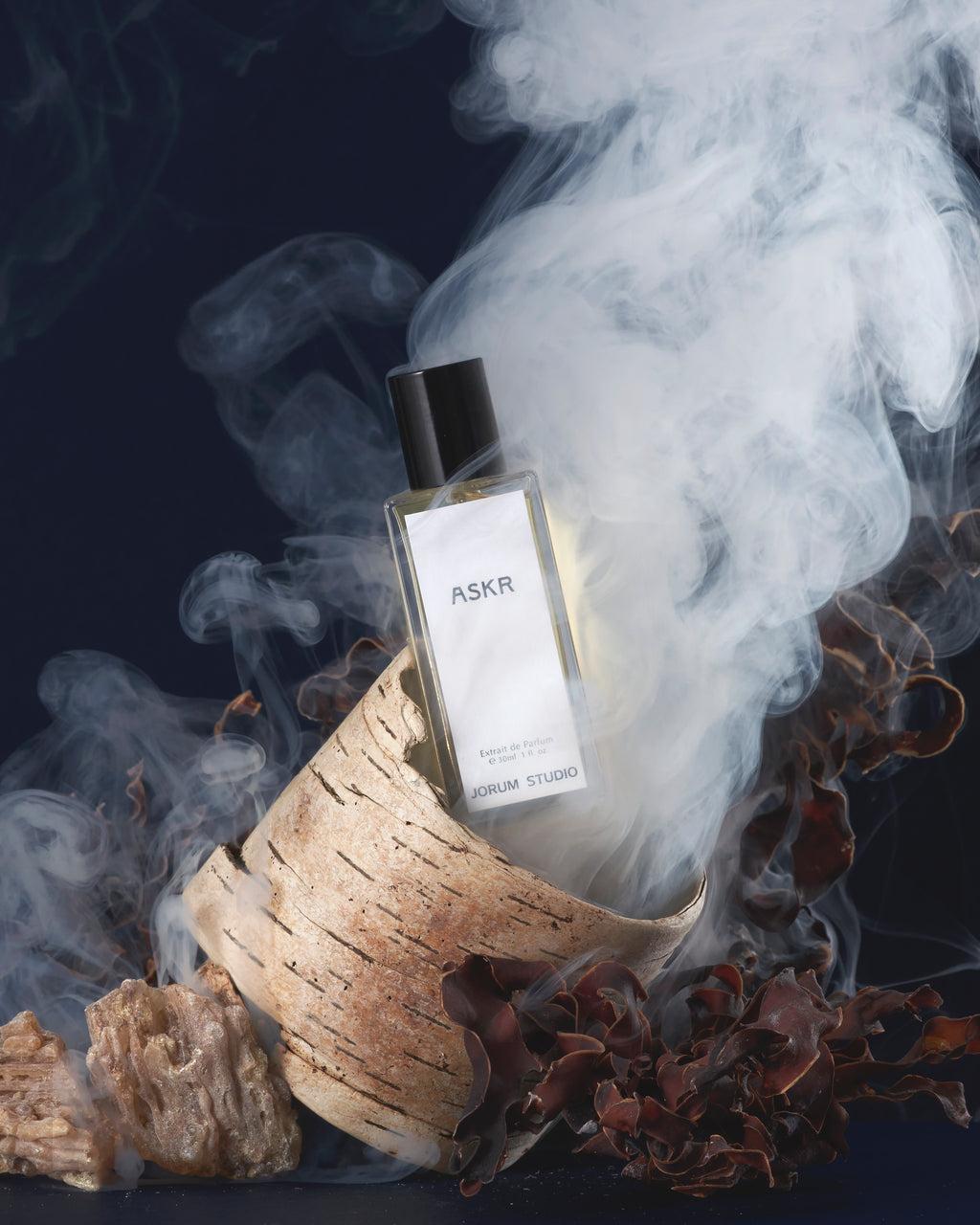 Jorum Studio Askr perfume bottle arranged in a still-life featuring wood shavings, seaweed and resin smoke